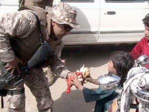 Soldier in Afghanistan offers a Beanie  Baby to an Afghani child. This Beanie Baby was donated by AnySoldier supporters. Photo used courtesy AnySoldier.com